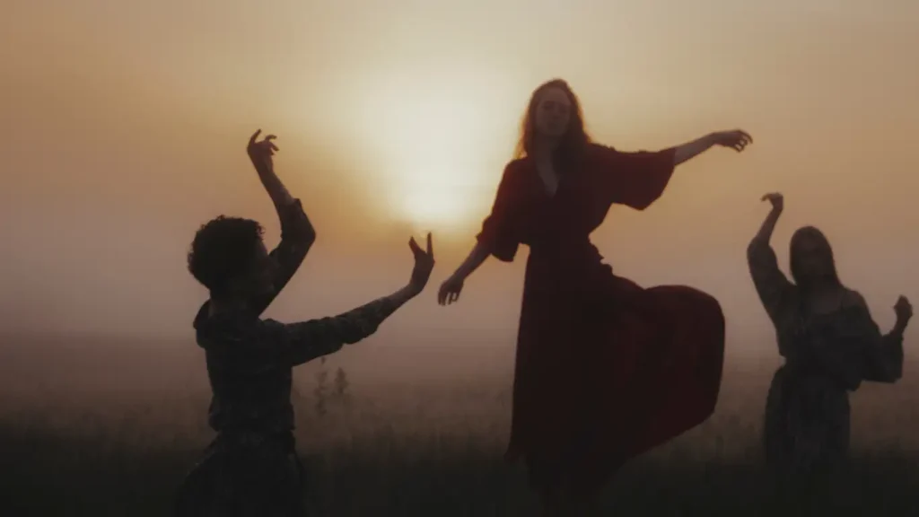 Three women dancing freely in nature at sunrise, symbolizing emotional release and personal liberation.